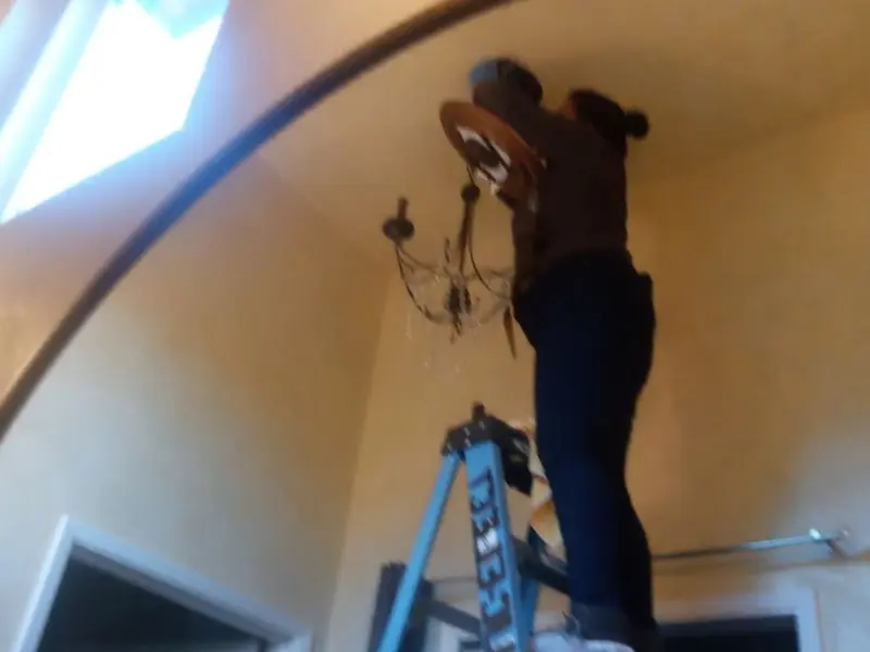 Electrician installing a chandelier in a Conestoga residence